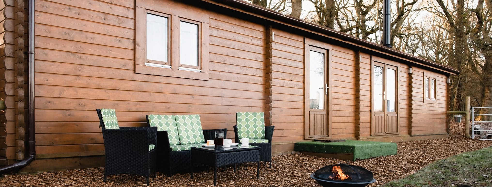 Timber exterior with a woodchip seating area and fire pit at Keepers Cabin