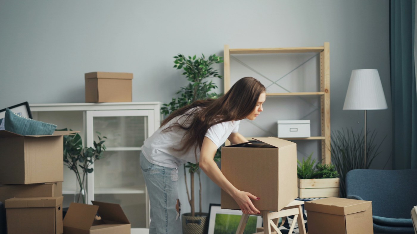 A woman moving boxes through a living room